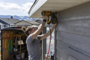 Construction Tech student putting up siding for Sheridan College program with Habitat for Humanity