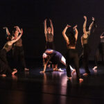 Photo of several dancers surrounding a spotlit dancer during a performance at Sheridan College