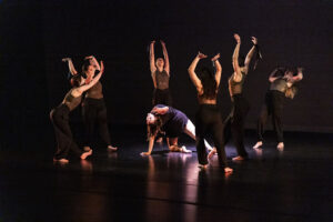 Photo of several dancers surrounding a spotlit dancer during a performance at Sheridan College