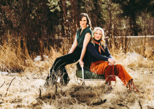 Edie Carey and Sarah Sample photo, outside sitting together on a chair in the grass