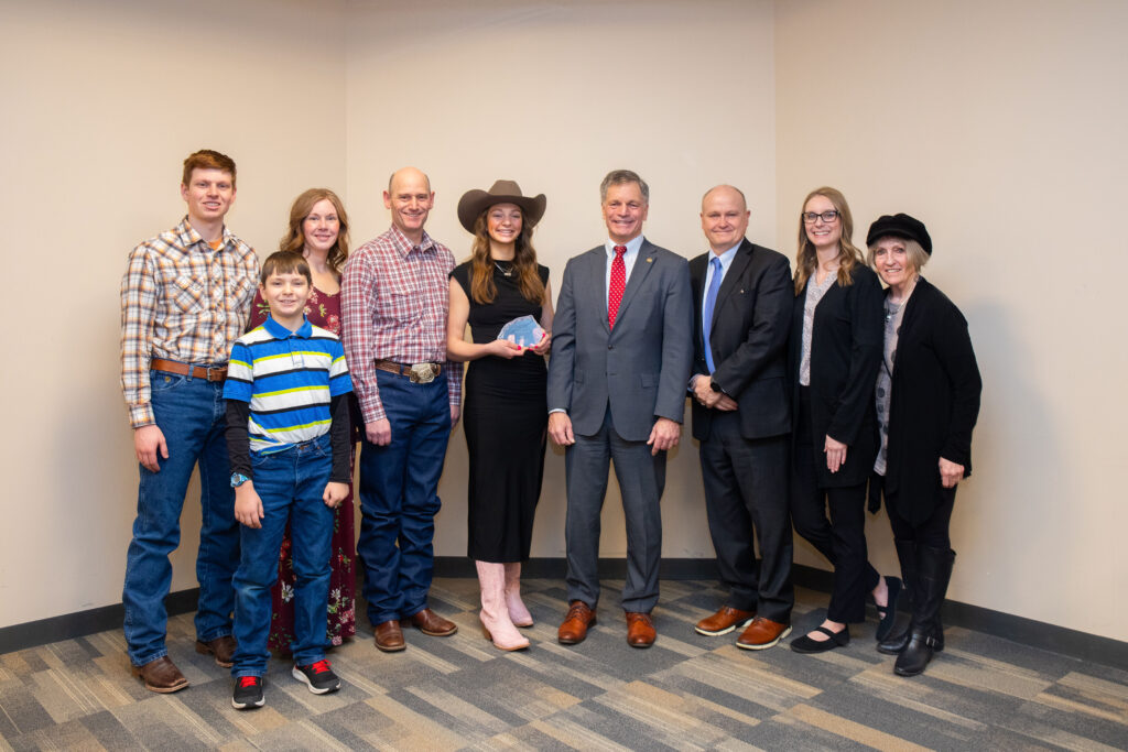 Tayler Coleman receiving the WACCT award with Governor Gordon, President Tribley, family members, and other representatives.