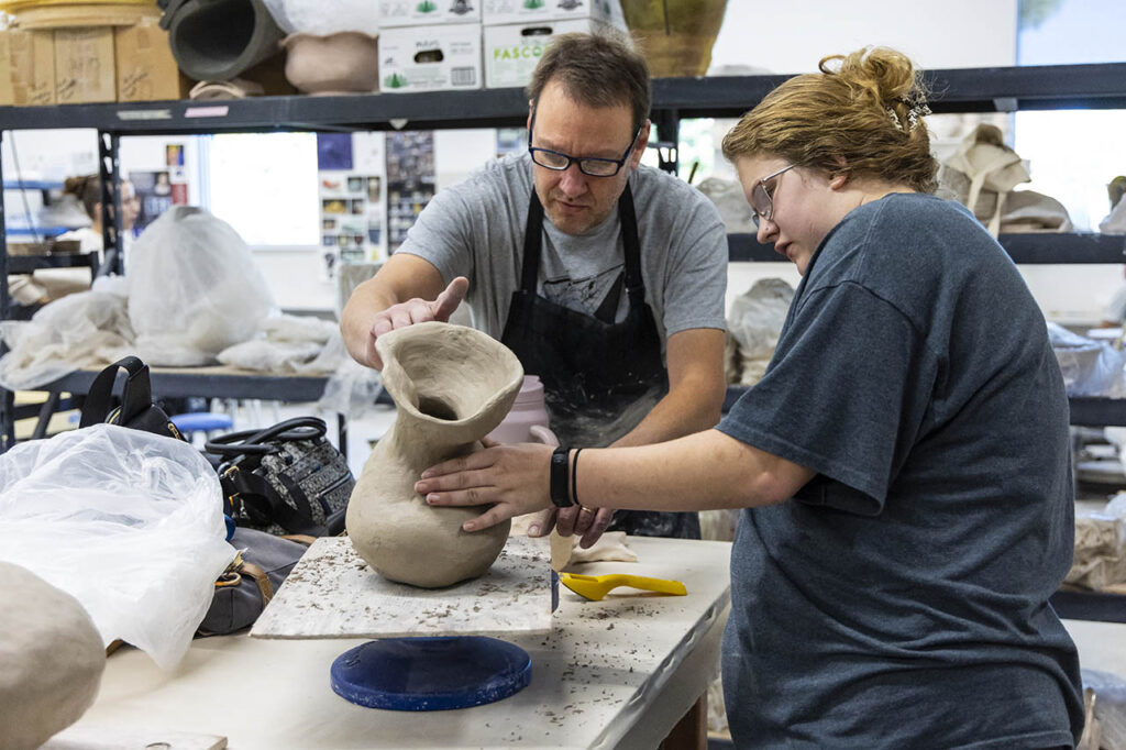 Ceramics instructor Rod Dugal working with a student and their coil pot.