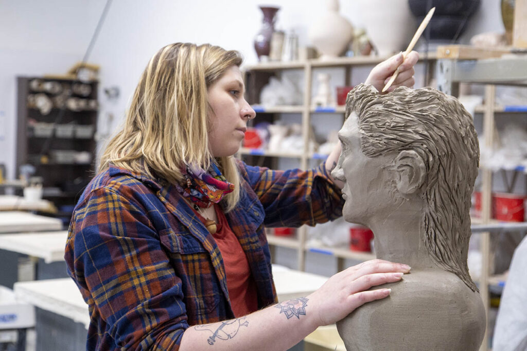 Cierra Roberts working on her clay sculpture