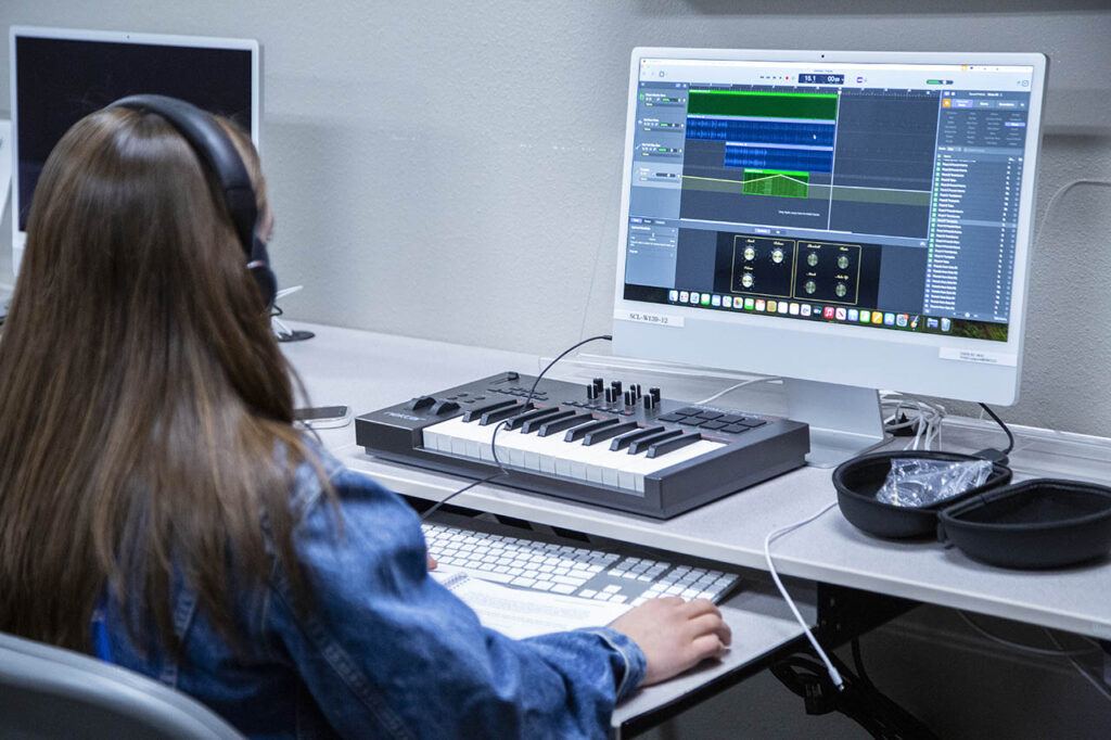 Student working on a mac computer doing audio recording