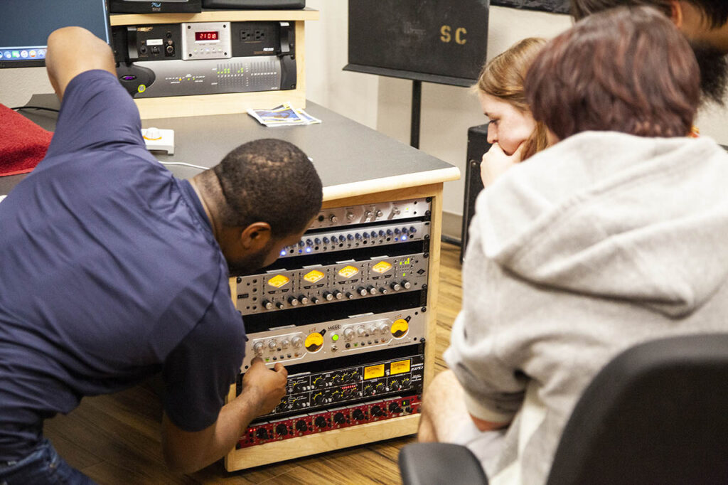 Student and instructor looking at universal audio inputs and other digital interfaces in the recording studio