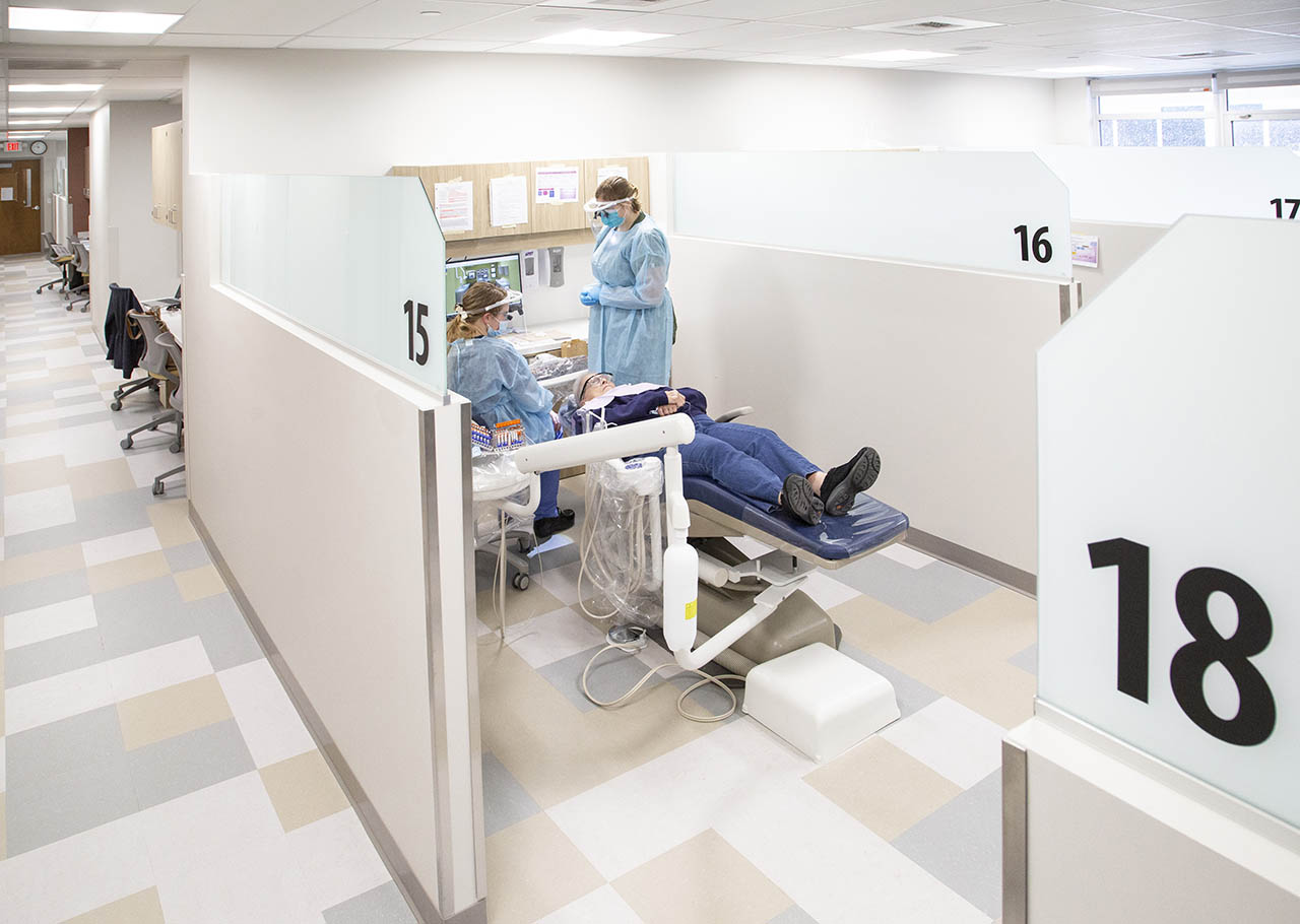 Image showing patient in dental chair with two students around them in the dental hygiene clinic