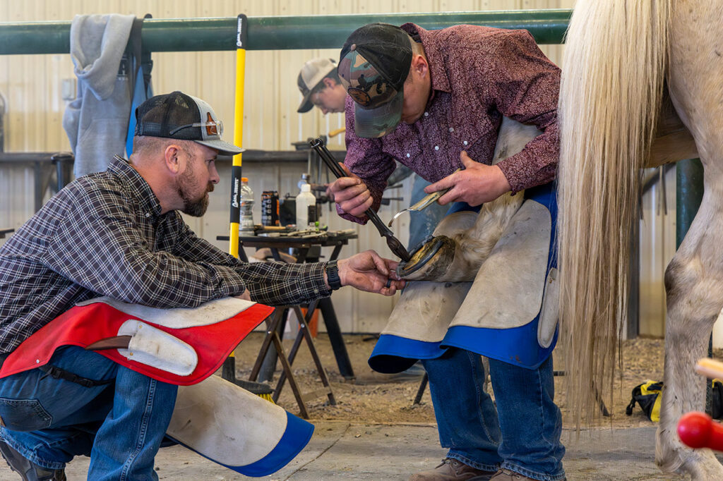 Sheridan College Farrier instructor Quint Gonzales helping a student shoe a horse.