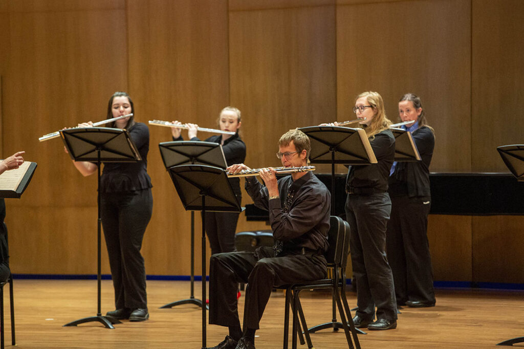 Several performers playing flute during a flute choir concert