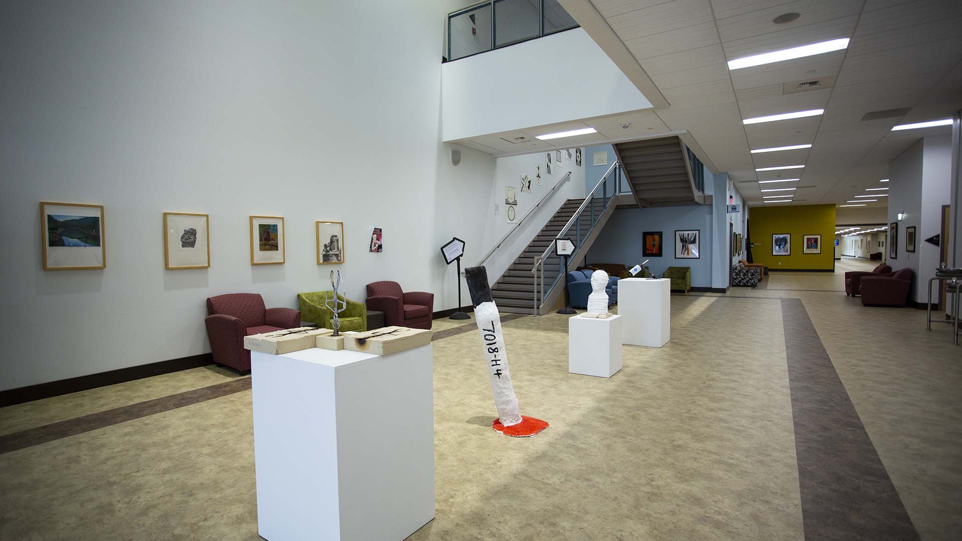 Whitney Center for the Arts lobby with student artwork on display and a staircase leading to the upper floor