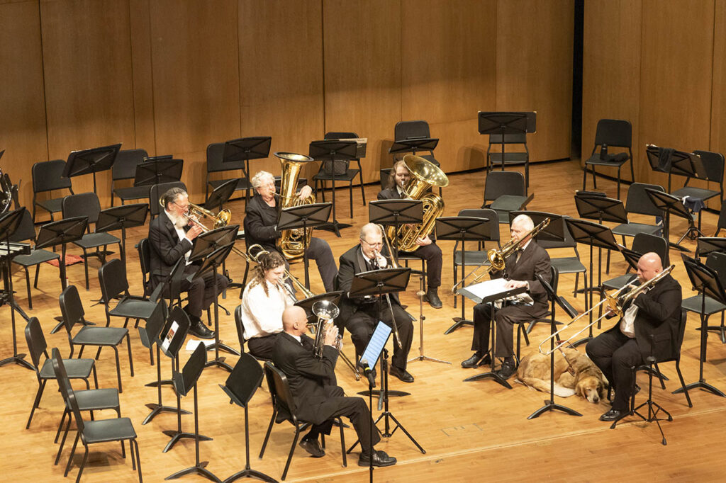 Seven trombone and other brass instrument players on stage in Kinnison Hall
