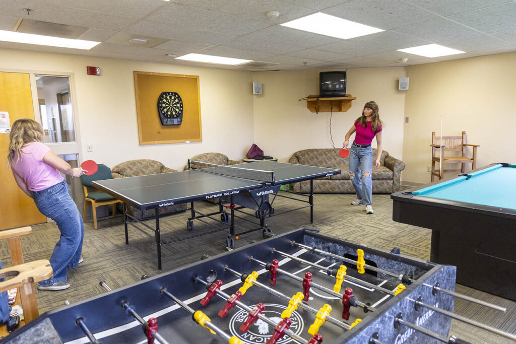 Two students playing ping pong in the game room at Founders Hall