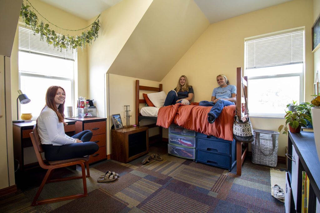 Three students hanging out in a bedroom in the Whitney Villas